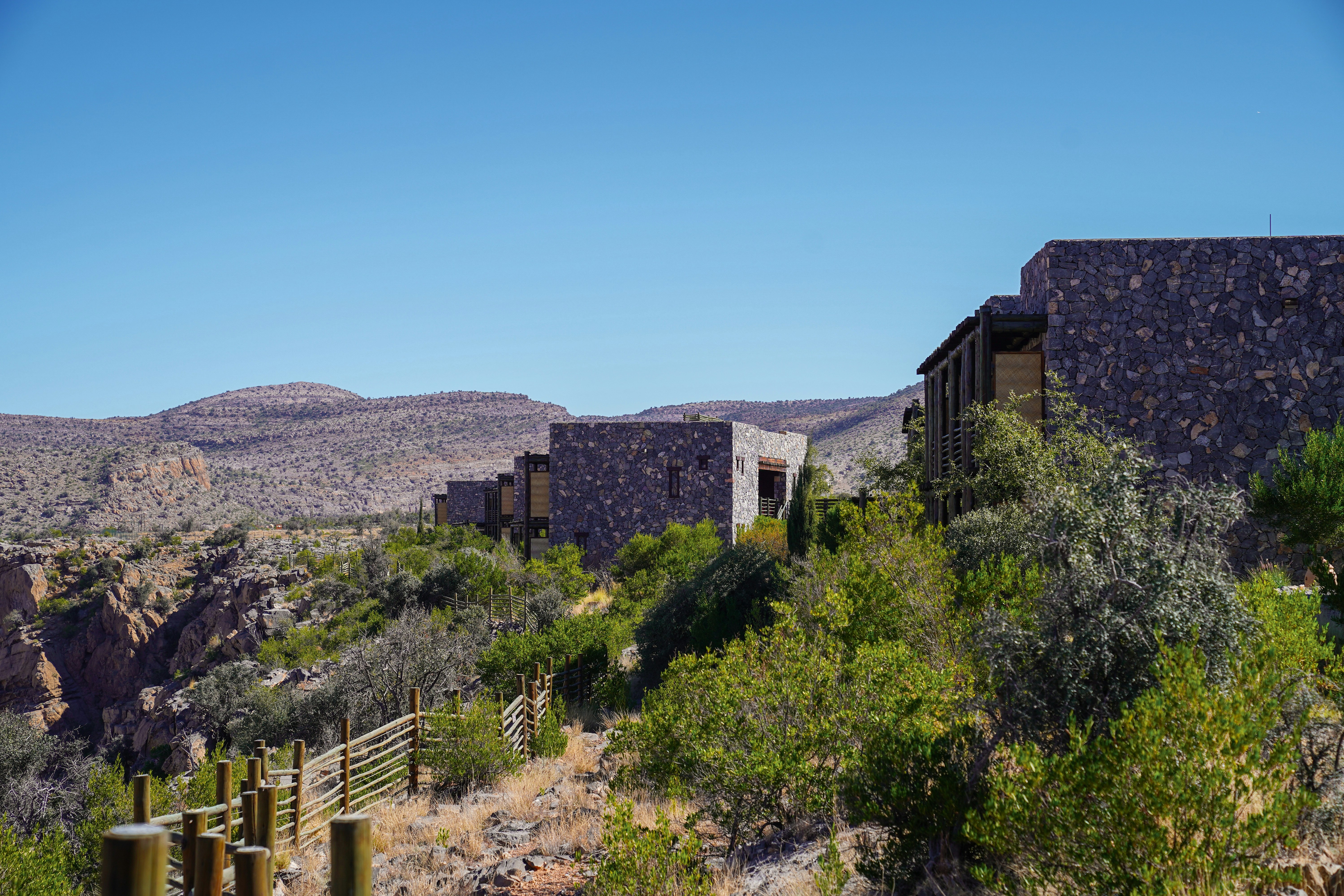 a building in the middle of a desert with mountains in the background, 