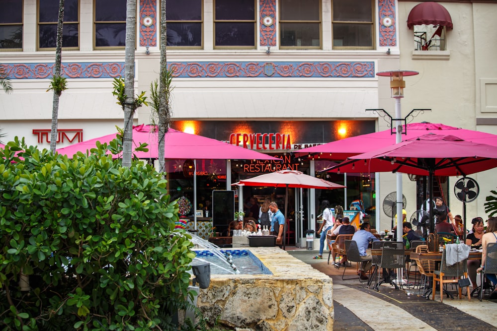 a group of people sitting at tables under umbrellas