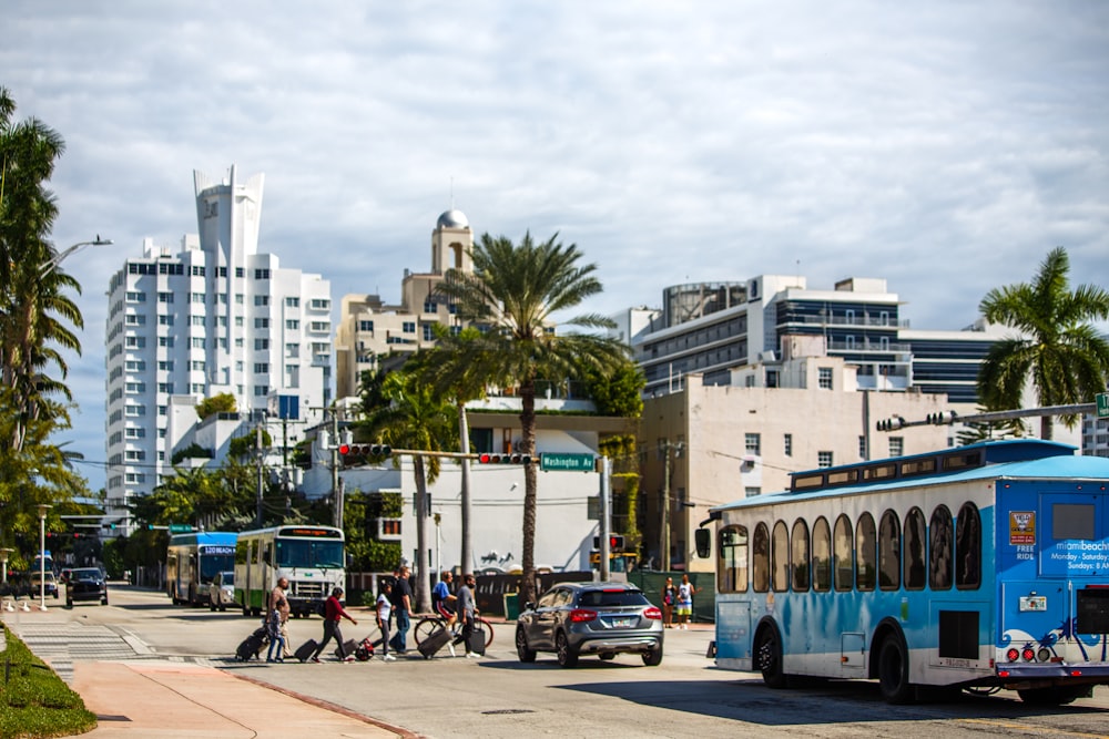 a blue bus driving down a street next to tall buildings