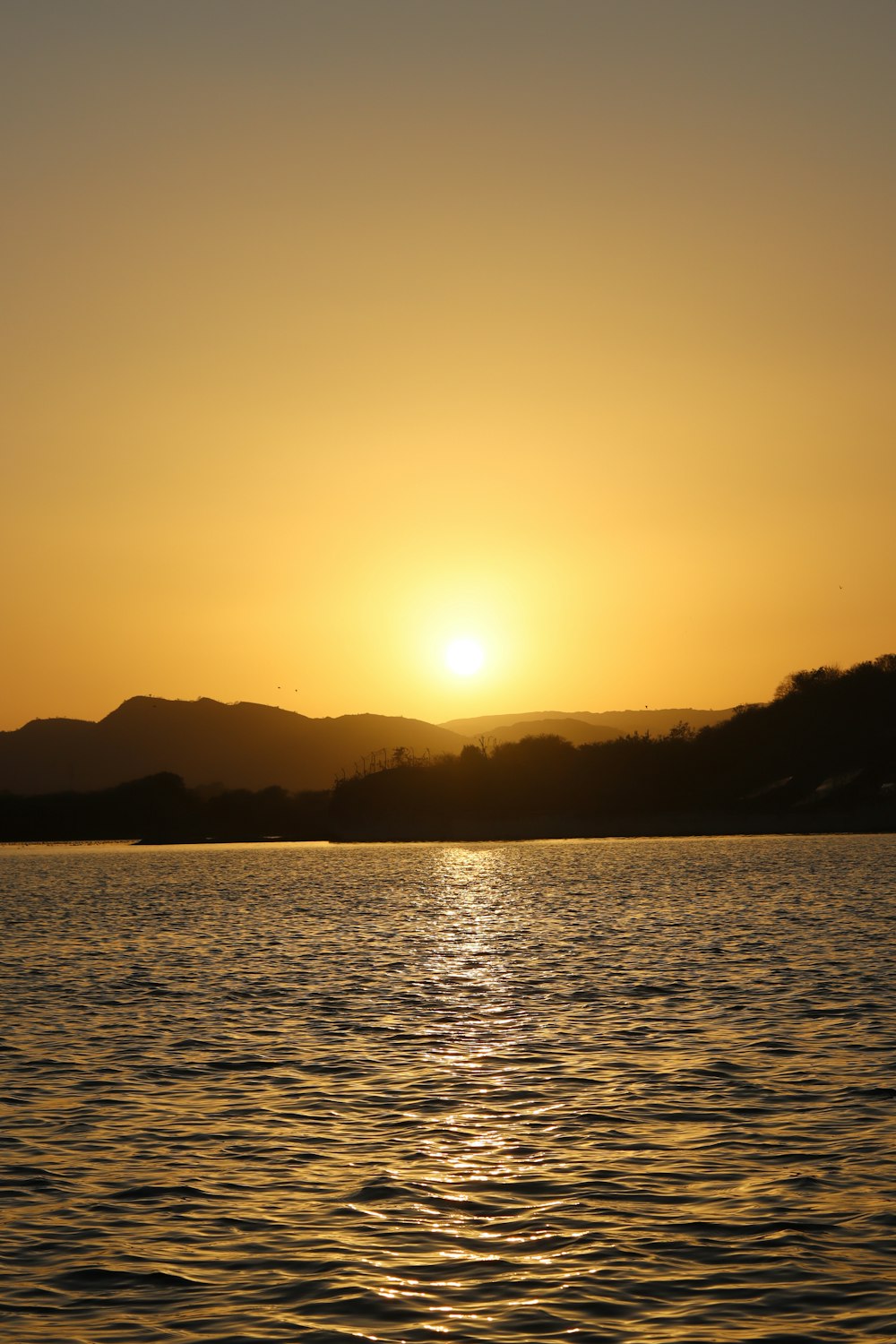 a large body of water with a sunset in the background