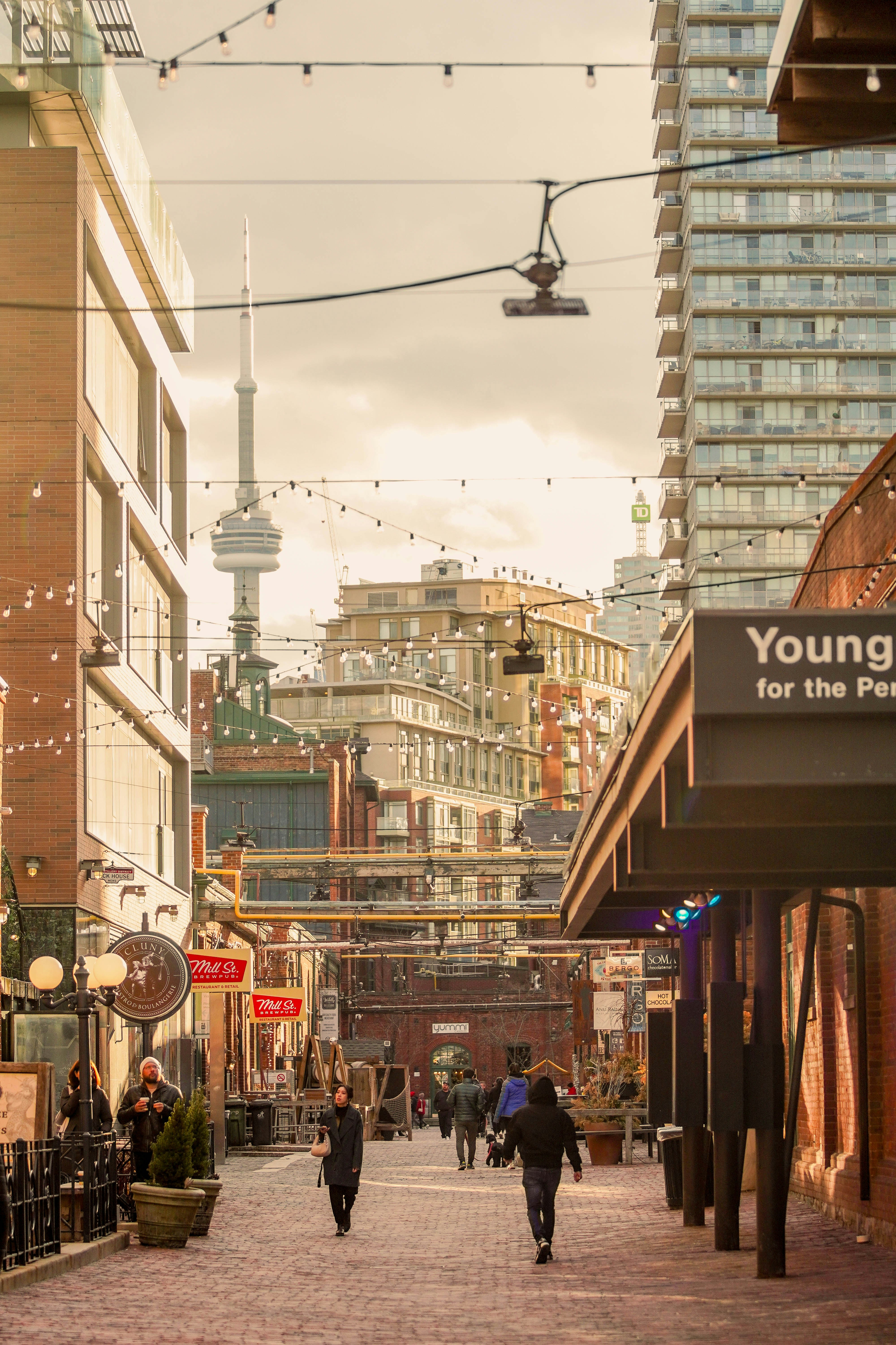 a group of people walking down a street next to tall buildings
