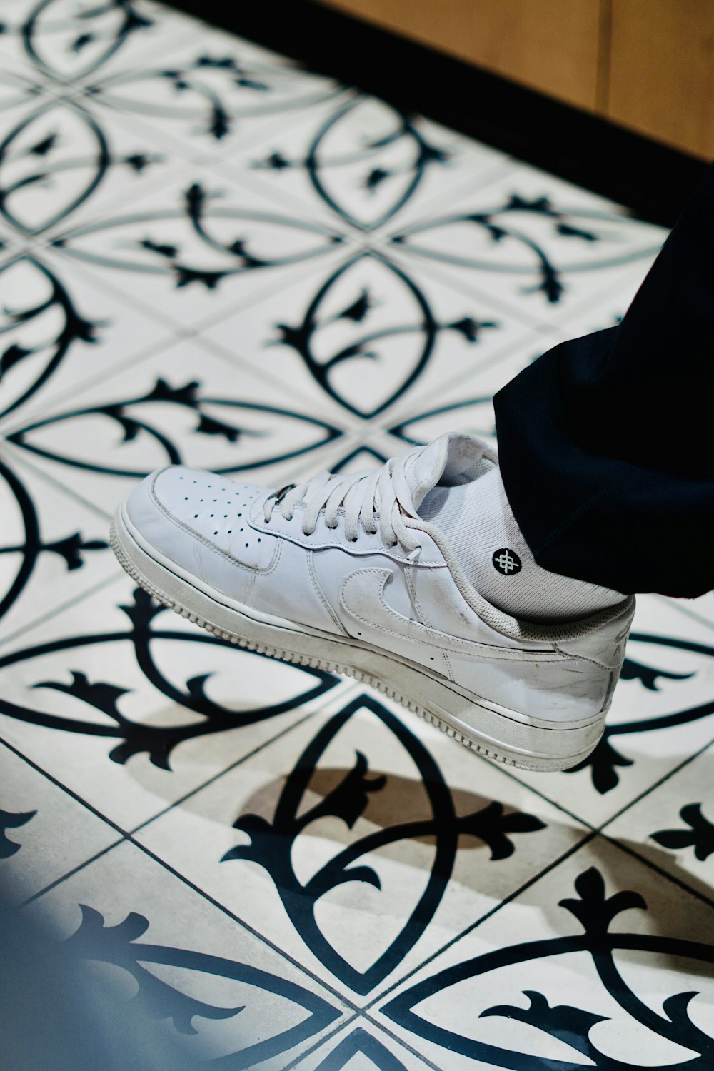 a person standing on a tiled floor with white shoes