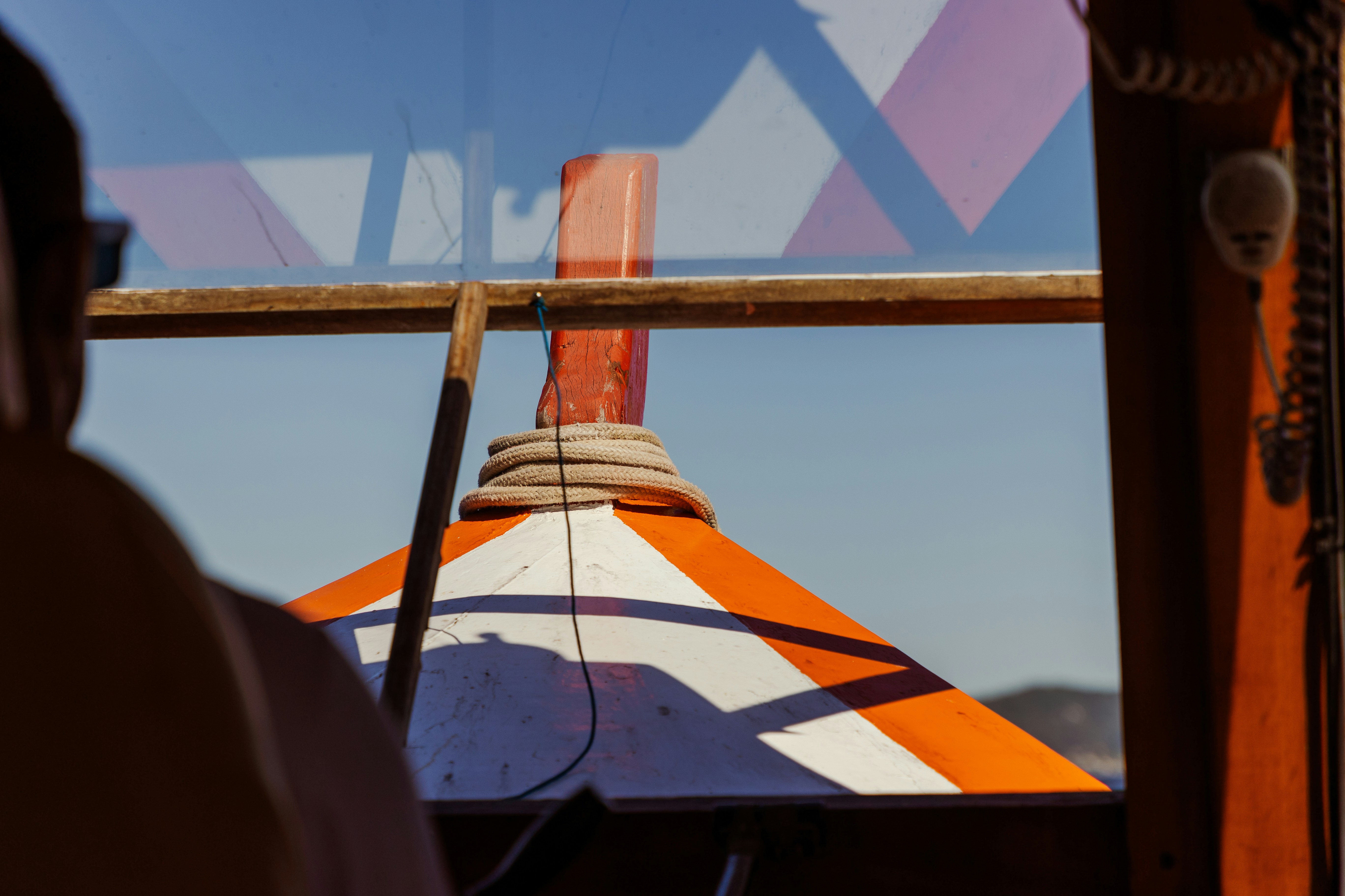 an orange and white striped umbrella is seen through a window