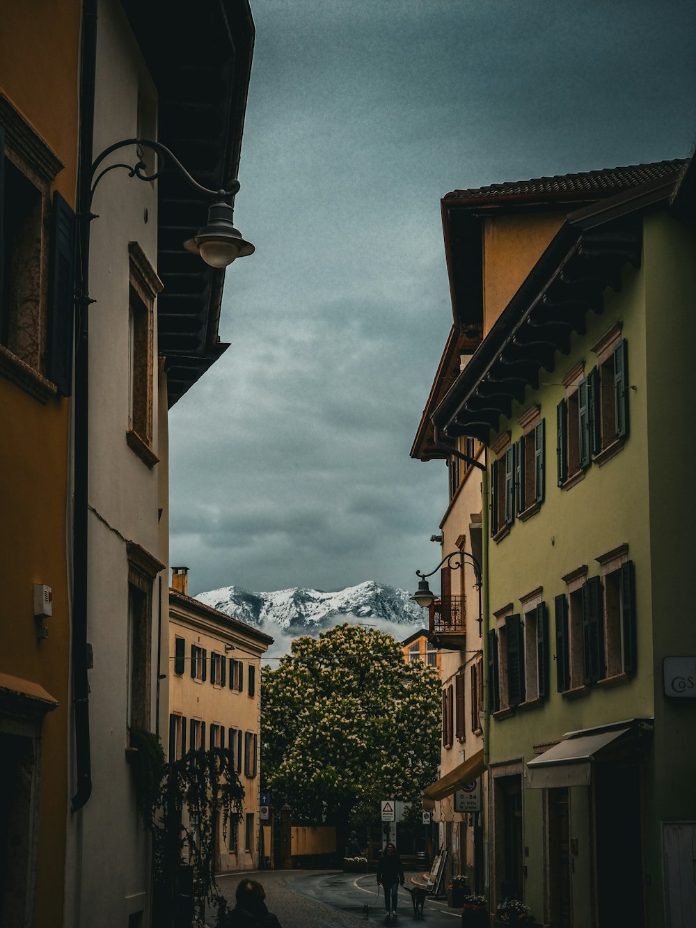 a narrow street with buildings and a mountain in the background