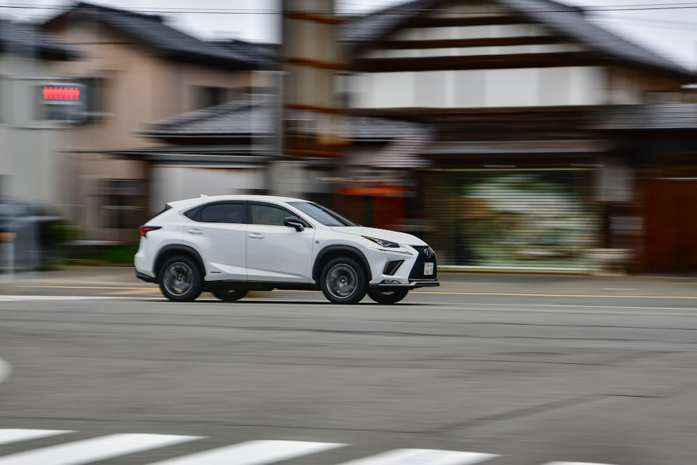 a white car driving down a street next to houses