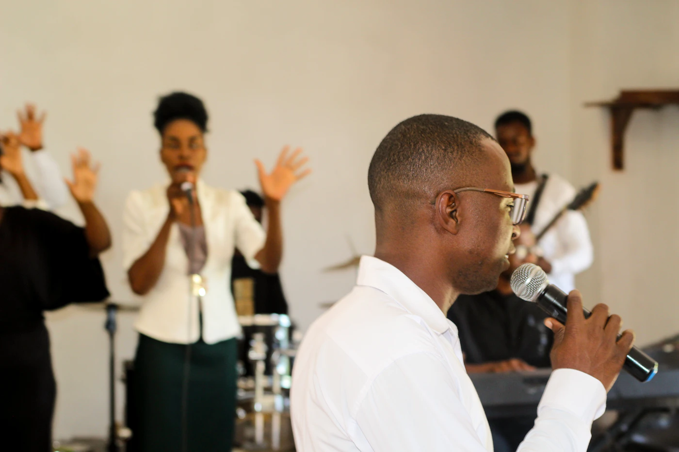 A church worship team leading praise with microphones, drums and guitar