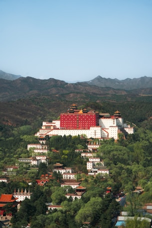 a large red building on top of a lush green hillside