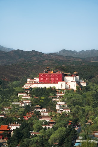 a large red building on top of a lush green hillside