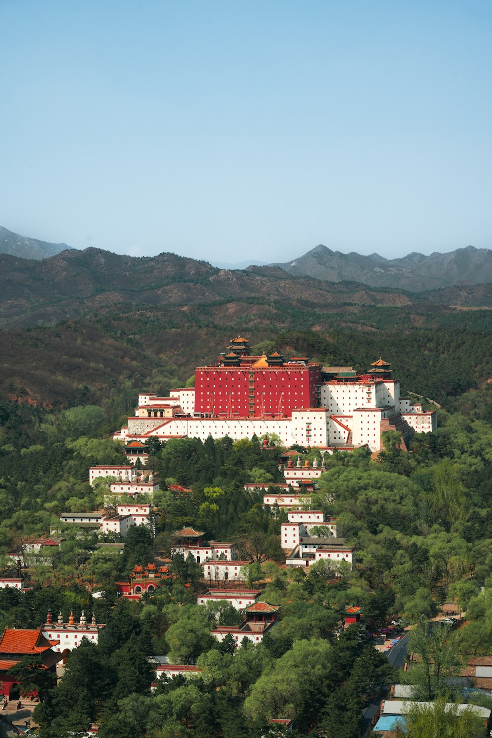 a large red building on top of a lush green hillside