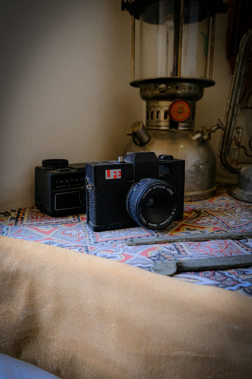 a camera sitting on top of a bed next to a lamp