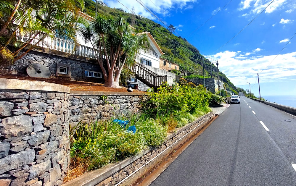 a car driving down a road next to a lush green hillside