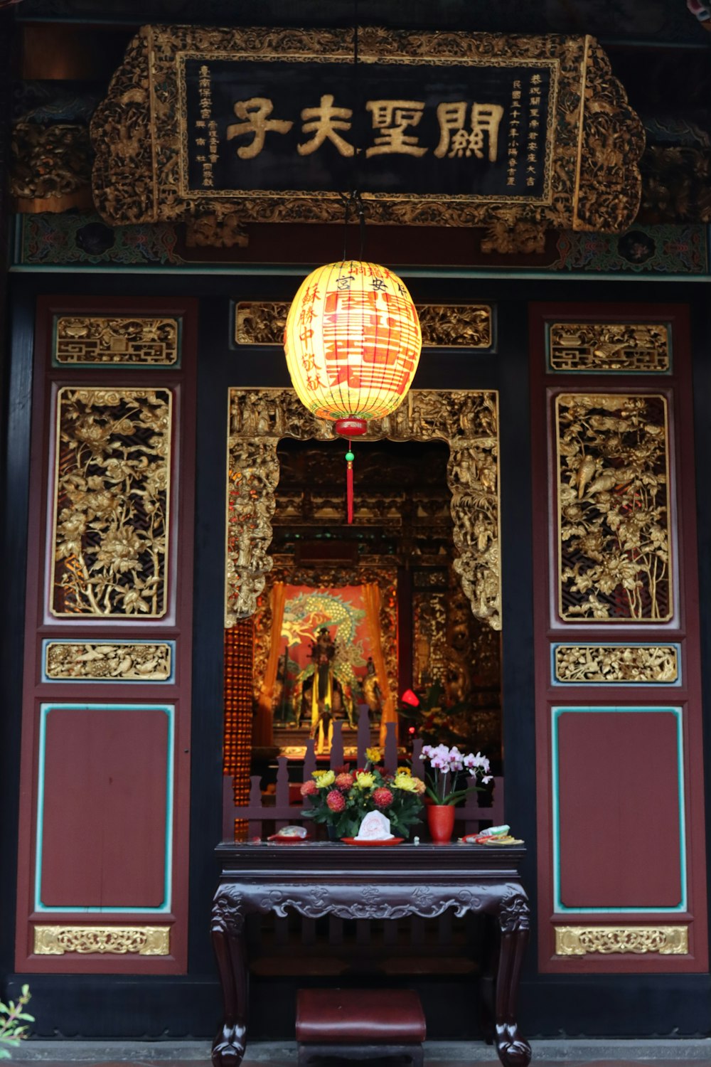 a shrine with a lantern and flowers in front of it