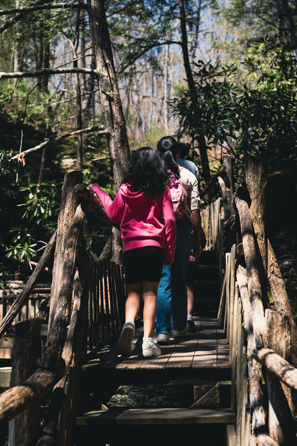 a group of people walking across a wooden bridge