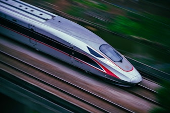 a silver and red train traveling down train tracks