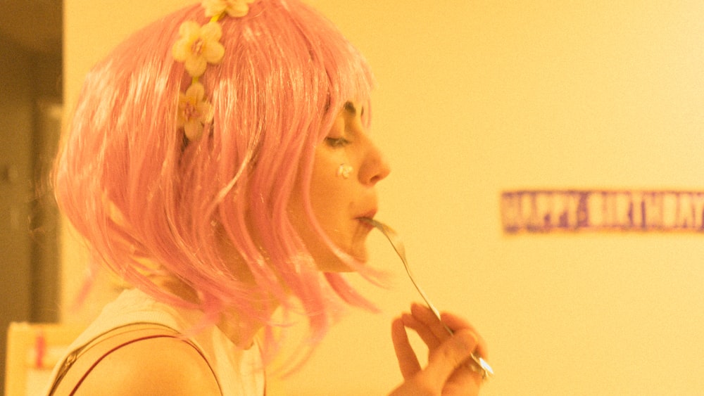 a woman with pink hair is brushing her teeth