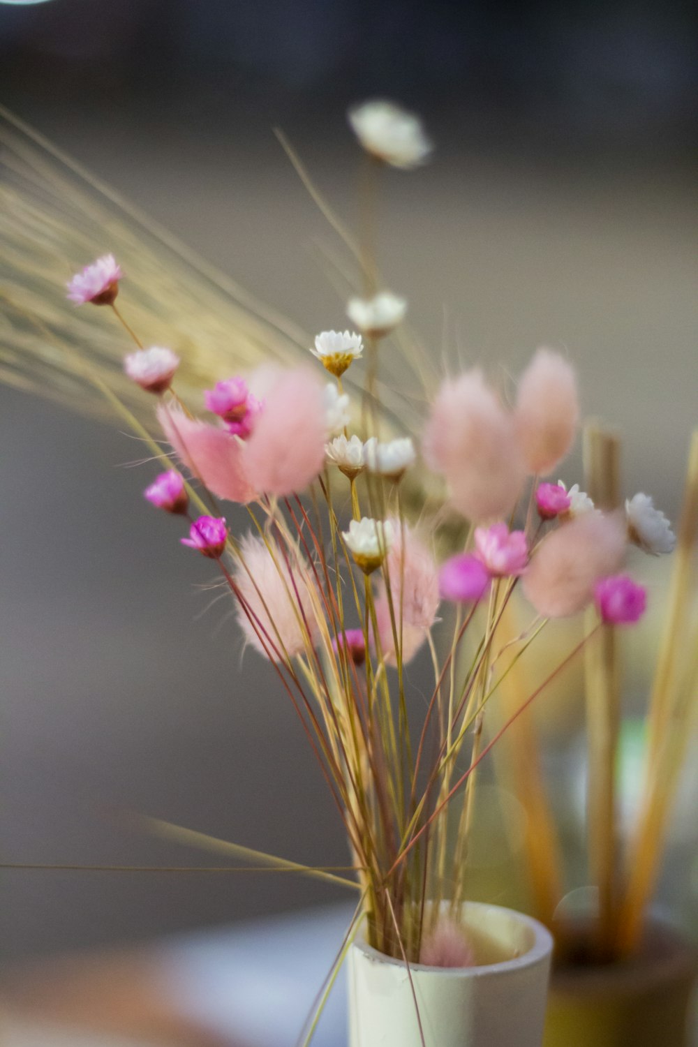 a white vase filled with pink flowers on top of a table