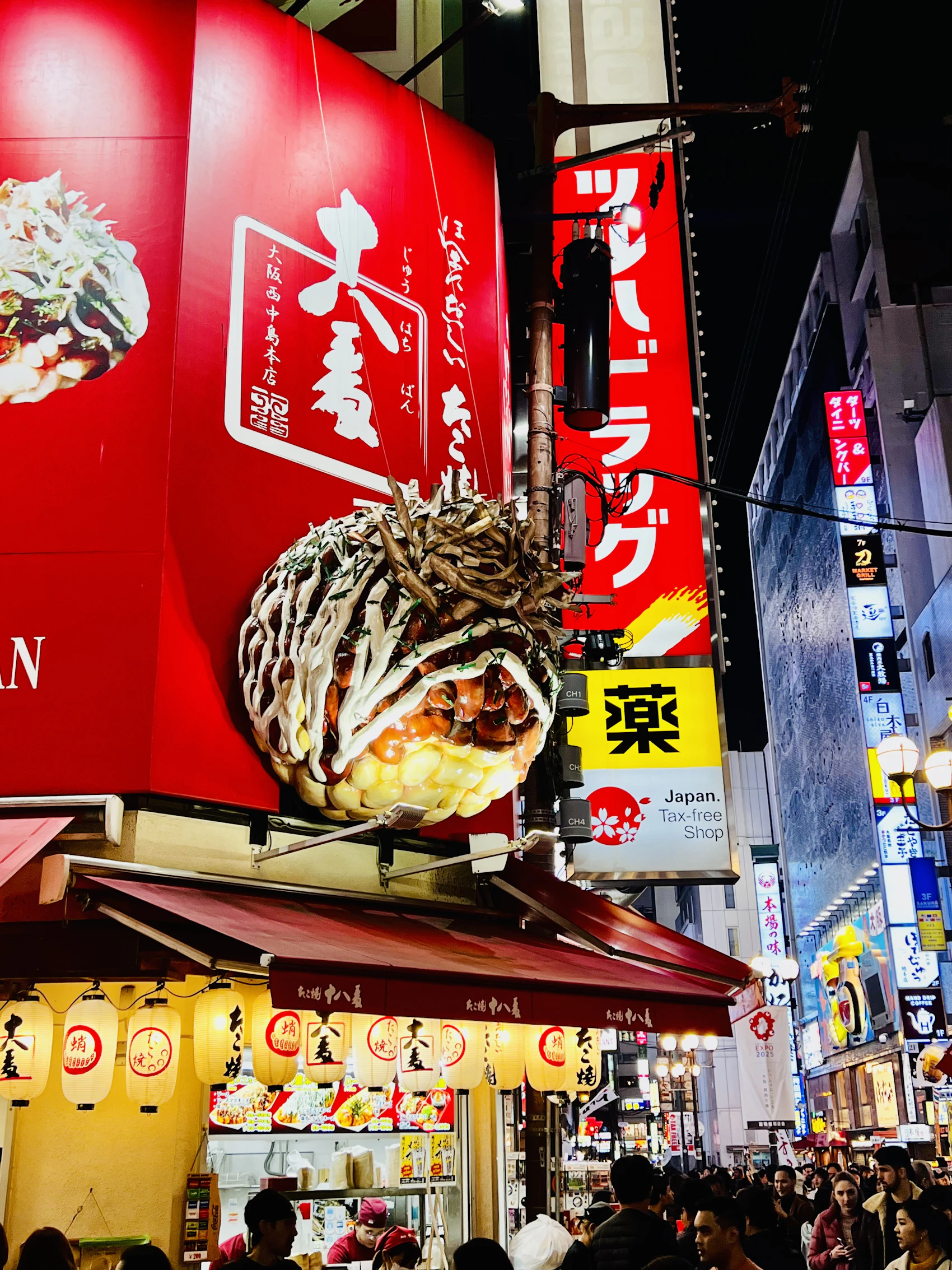 A giant okonomiyaki sign above a busy restaurant street in Osaka