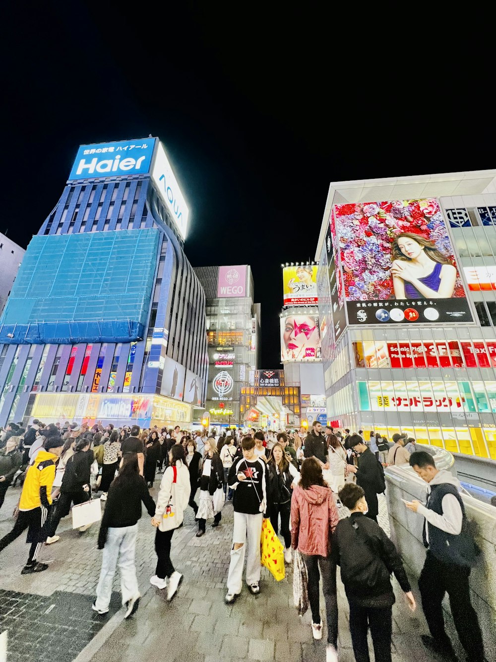 a crowd of people walking down a street next to tall buildings