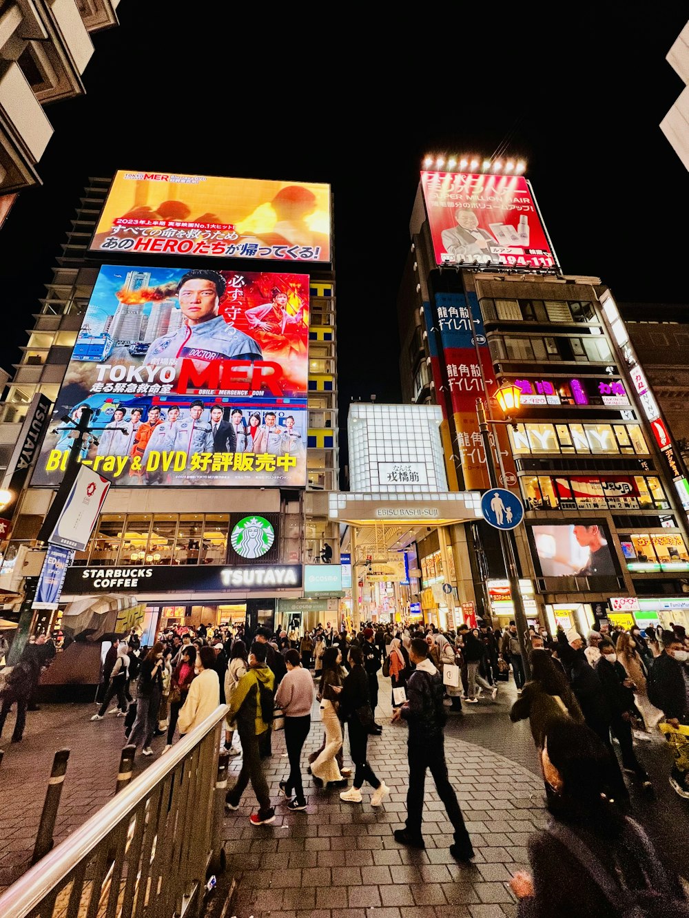 a crowd of people walking down a street next to tall buildings