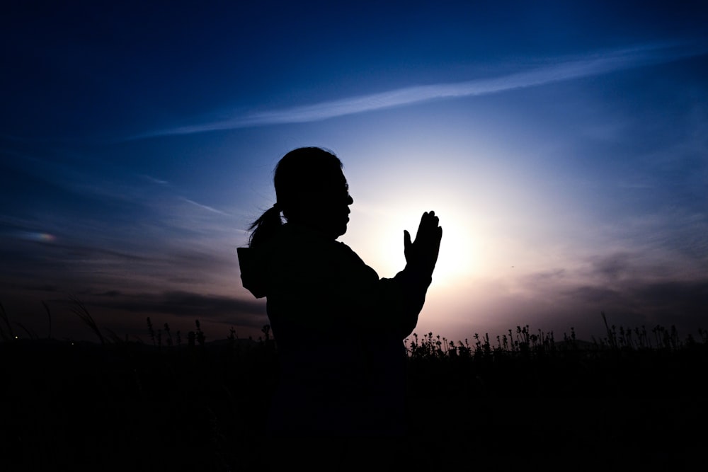 a woman standing in a field at sunset