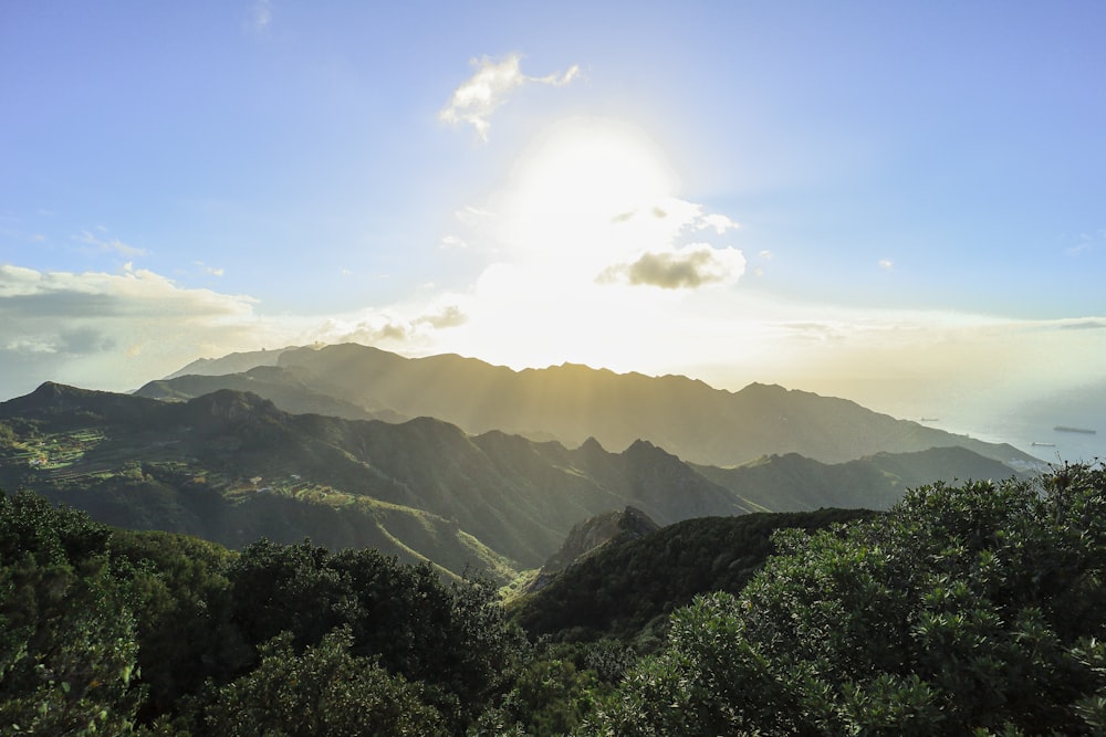 the sun is shining over a mountain range