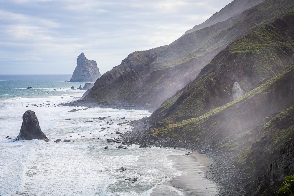 a view of the ocean with a rocky cliff in the background