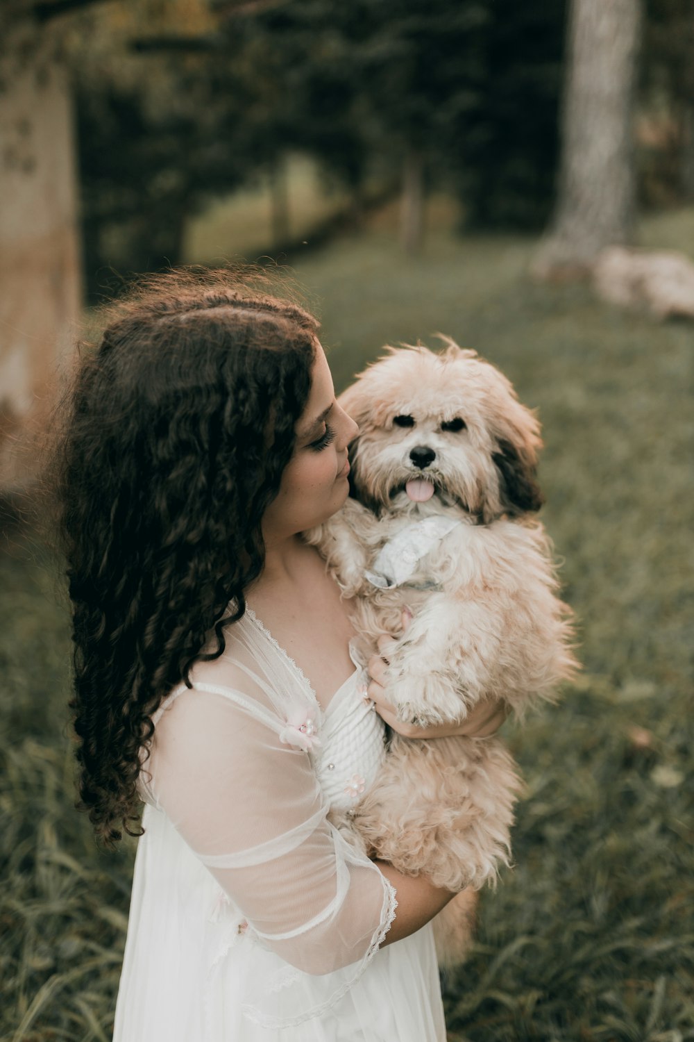 a woman in a white dress holding a dog