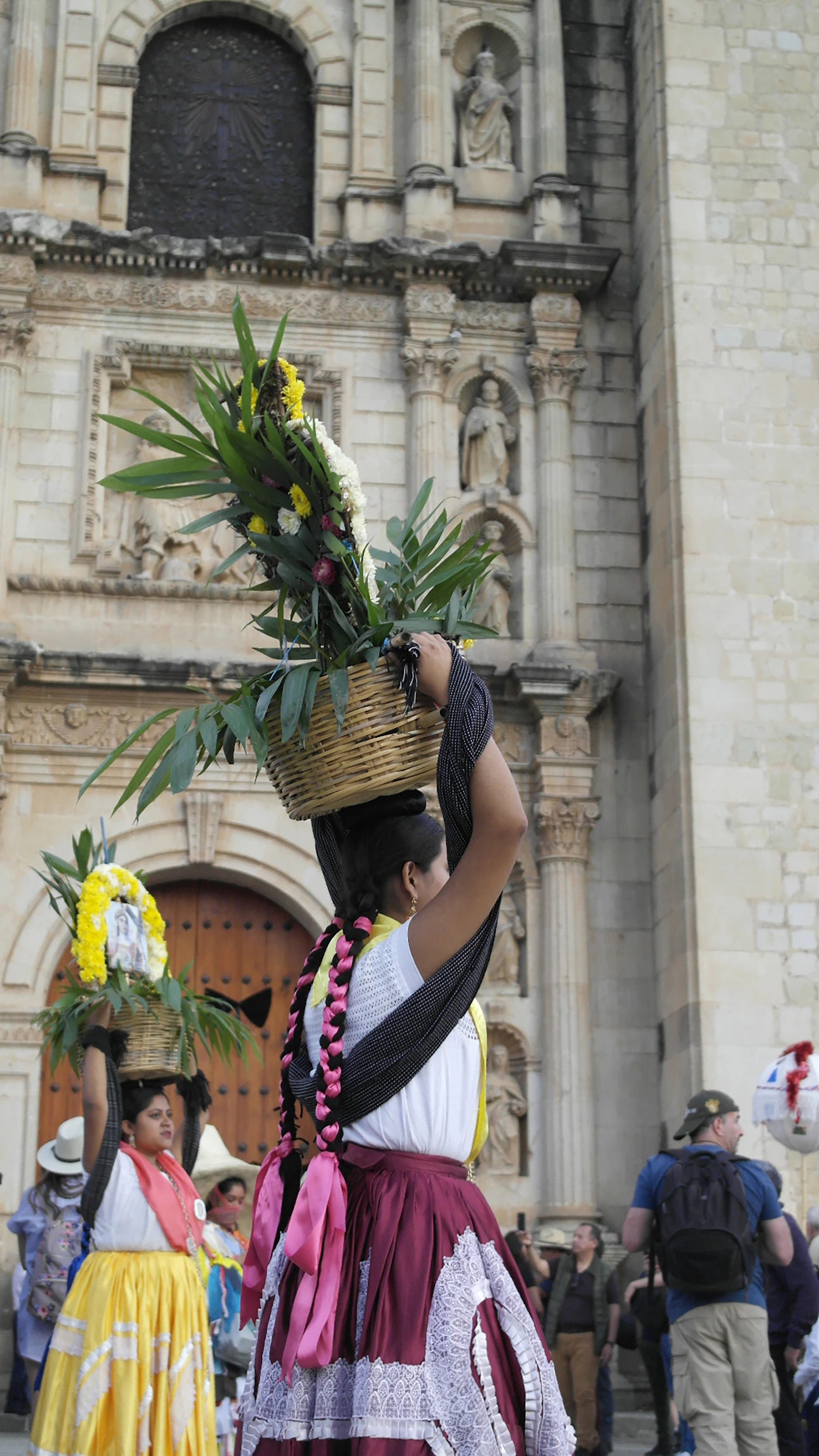 A Oaxacan woman in traditional Chinas Oaxaquenas embroidered dress and headdress holding a large basket of flowers outside Santo Domingo church in Oaxaca