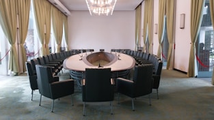 a conference room with a round table surrounded by black chairs