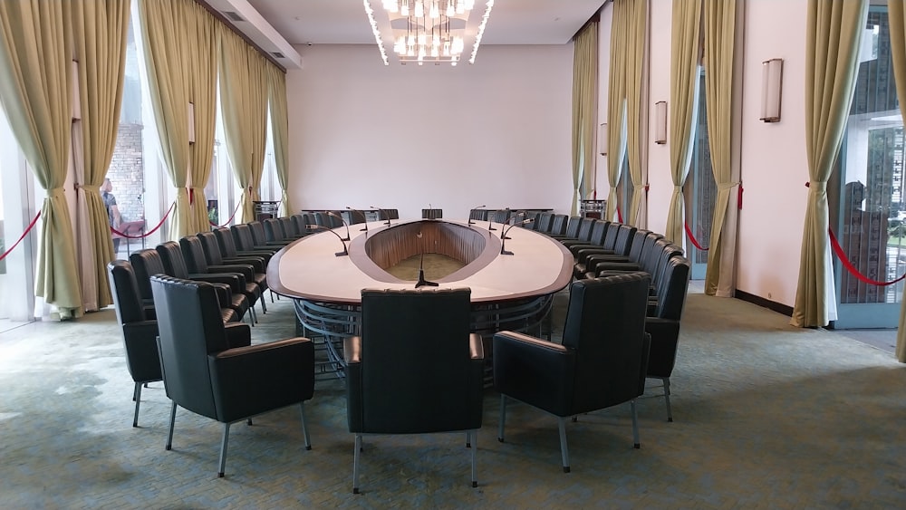 a conference room with a round table surrounded by black chairs