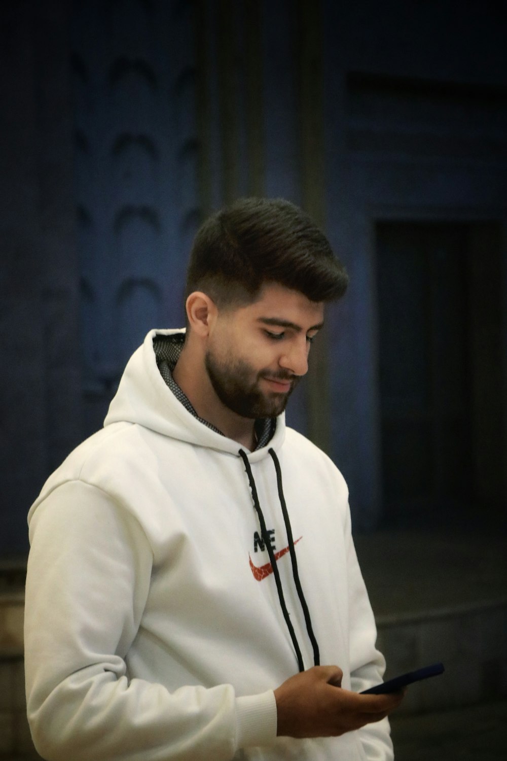 a man in a white hoodie looking at his cell phone