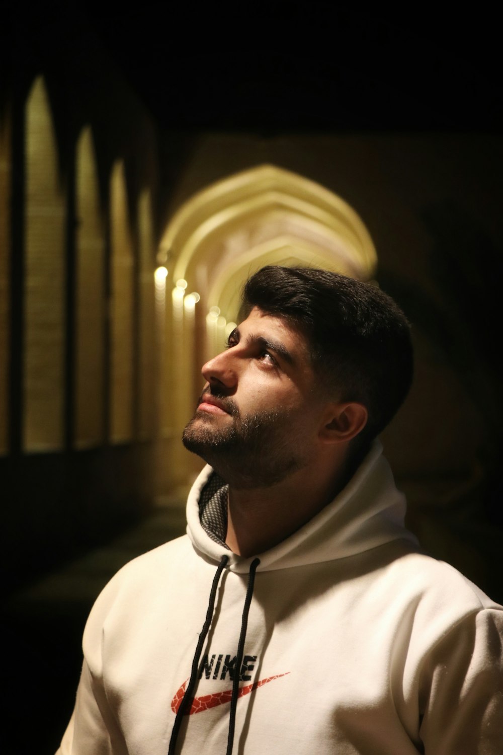 a man in a white hoodie standing in front of a church