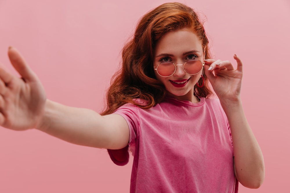 a woman in a pink shirt is holding her hands out