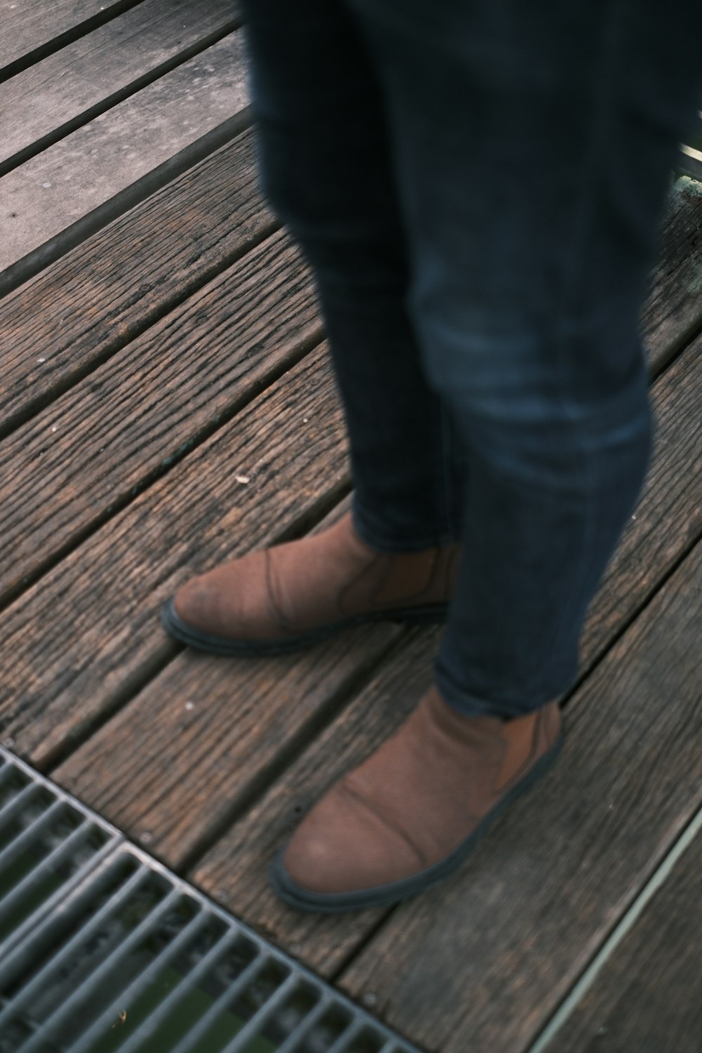 a person standing on a wooden deck wearing brown shoes