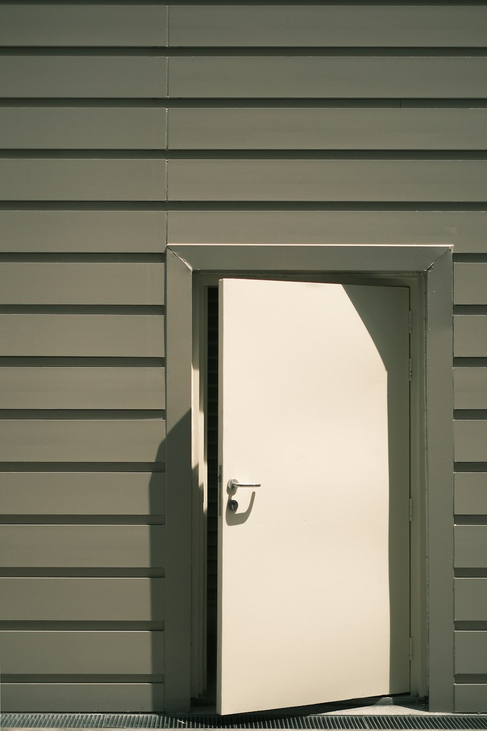 a white door is open in front of a gray building