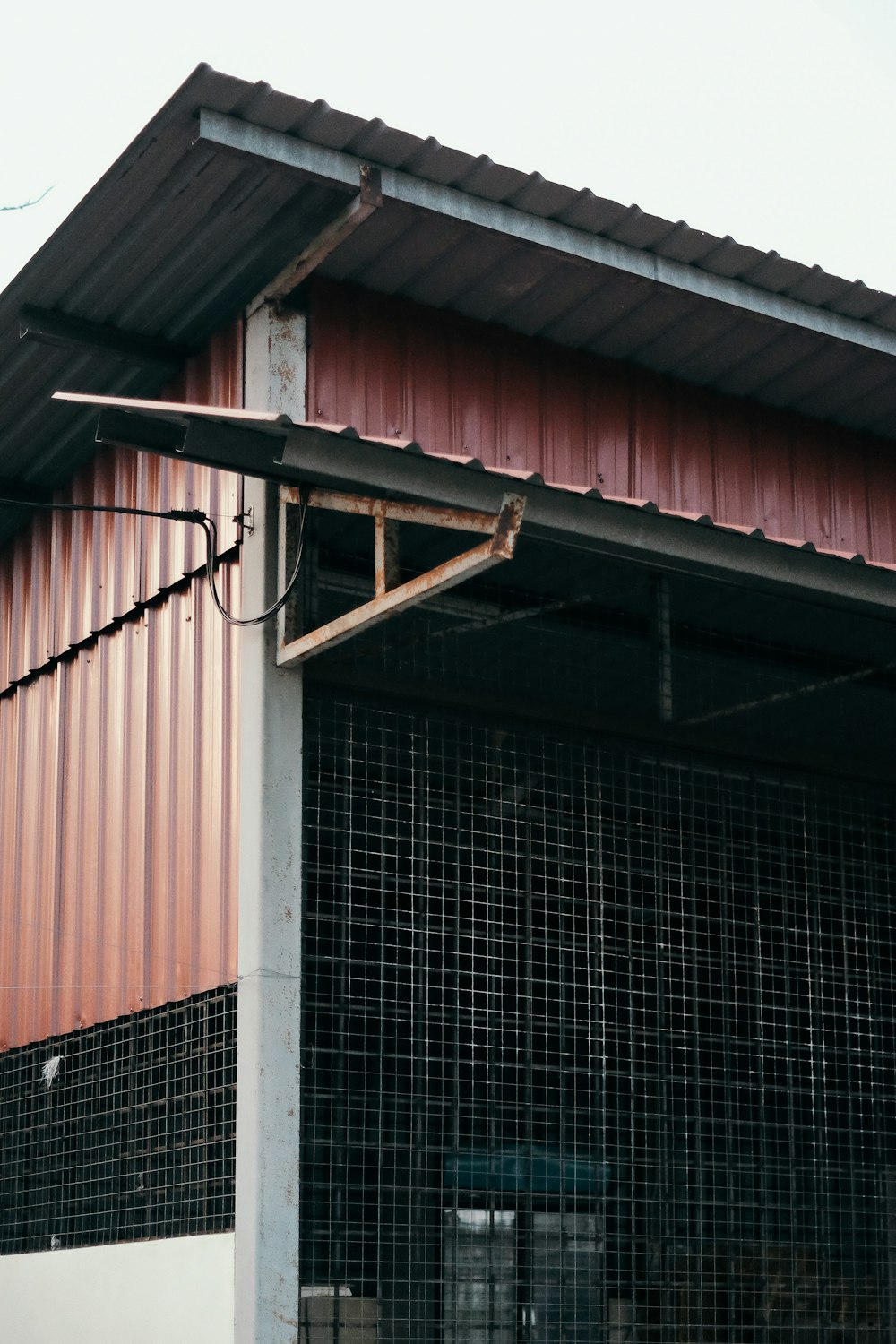 a red building with a metal roof and a clock on the side of it