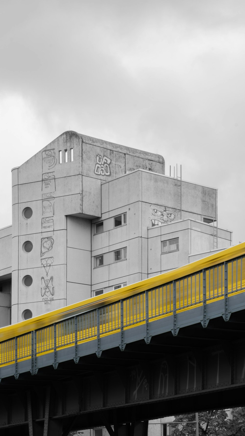 a yellow and gray train traveling over a bridge