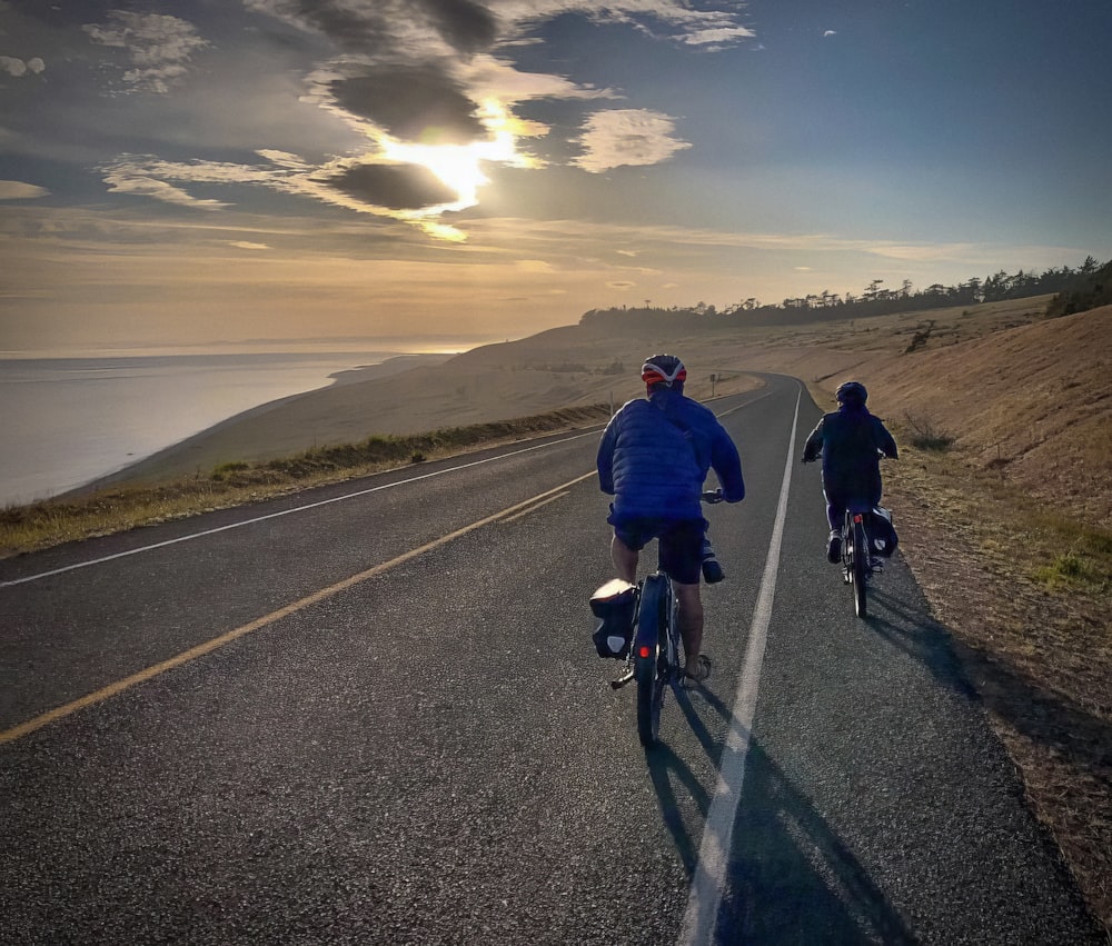 a couple of people riding bikes down a road