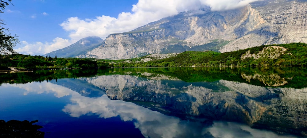 a mountain range is reflected in the still water of a lake