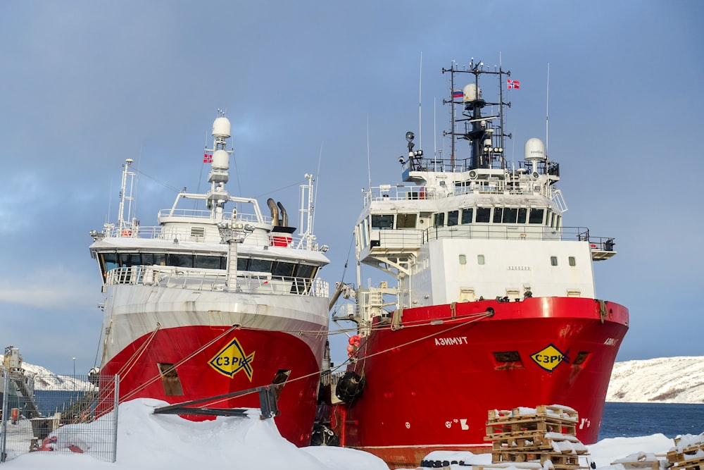 two large red and white boats in the snow
