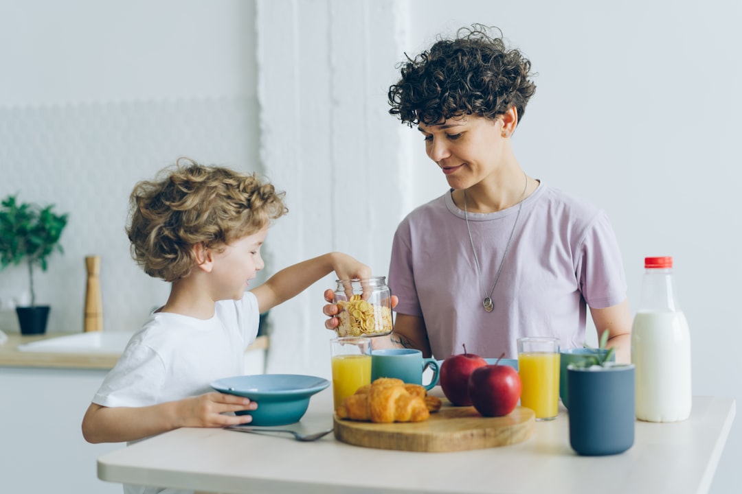 Happy family mother and son eating cereal with milk at home talking