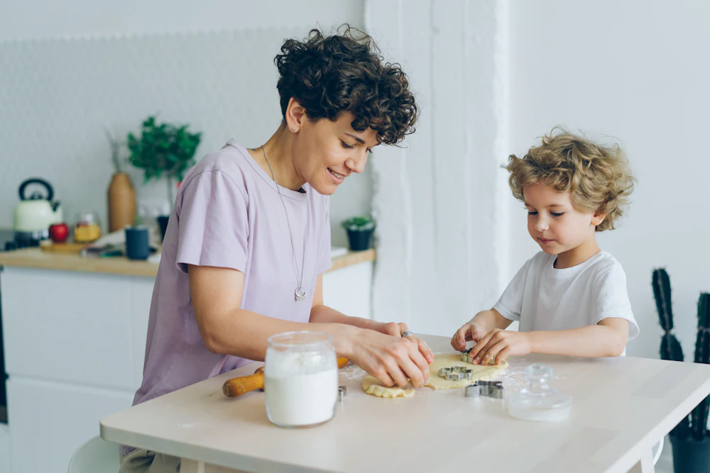 Een begeleider en een kind bereiden samen eten voor aan de keukentafel
