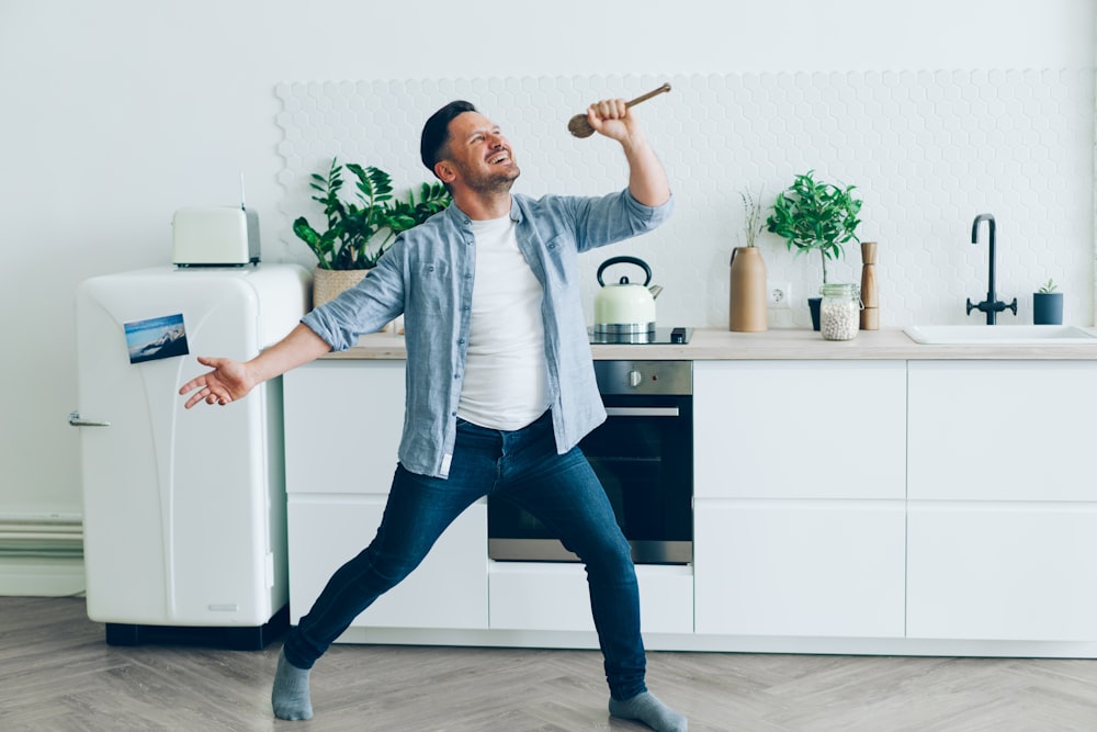 a man standing in a kitchen holding a hammer