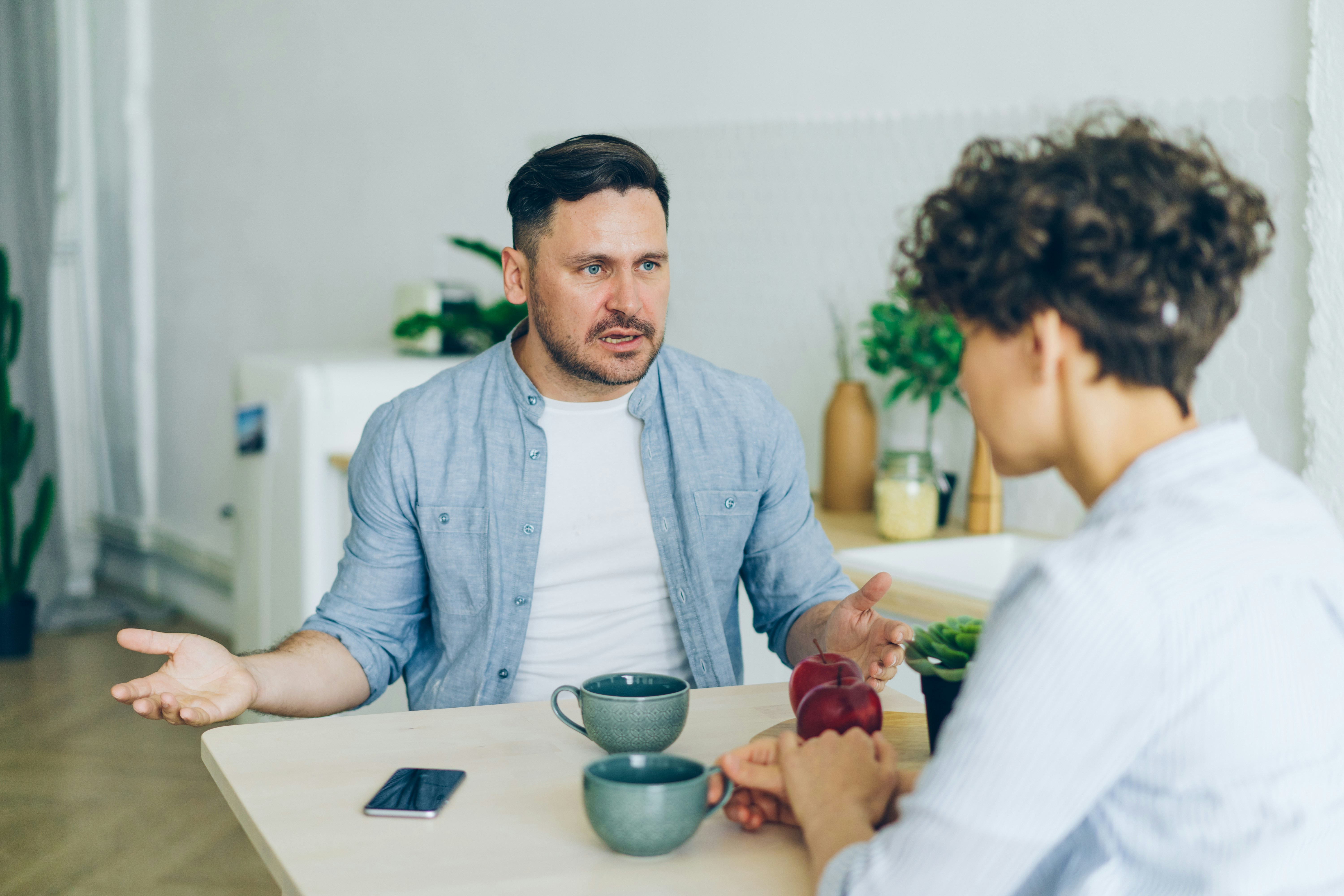 Annoyed man yelling at unhappy wife in kitchen fighting gesturing