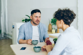 a man sitting at a table talking to a woman