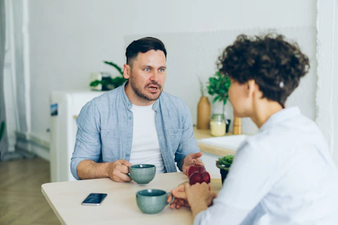 a man sitting at a table talking to a woman
