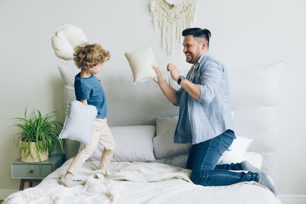 a man and a child playing with pillows on a bed