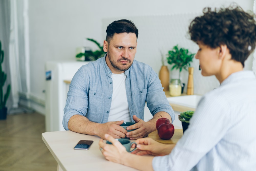 a man sitting at a table talking to a woman