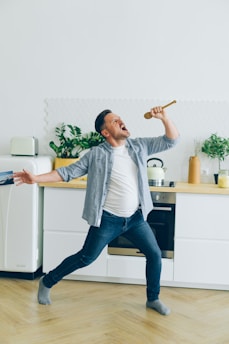 a man is dancing in the kitchen with a hammer in his hand