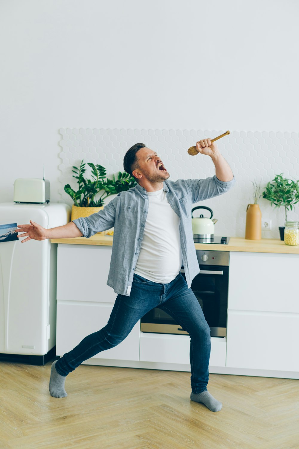 a man is dancing in the kitchen with a hammer in his hand